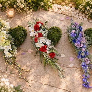 Puede incluir: Tres arreglos en forma de corazón cubiertos de musgo y decorados con flores artificiales. El corazón izquierdo tiene flores blancas y crema, el central flores rojas y blancas, y el derecho presenta diversos tonos de flores moradas y azules.