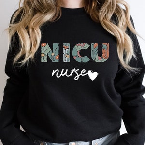 May include: Black sweatshirt with the text "NICU nurse" in white with floral accents around the letters and a small white heart.