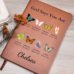 May include: A brown leather journal with the text "God Says You Are" and a variety of colorful butterflies with bible verses printed below each. The name "Chelsea" is printed at the bottom of the journal.