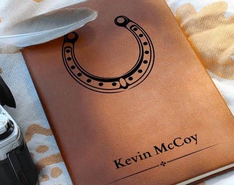 May include: A brown leather journal with a horseshoe design and the name "Kevin McCoy" engraved on the front.