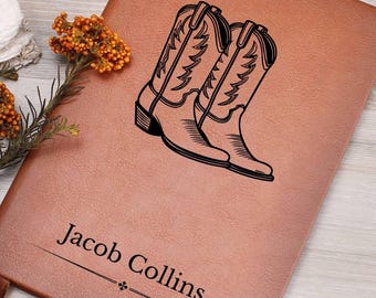 May include: A brown leather journal with a pair of cowboy boots and the name "Jacob Collins" engraved on the front.