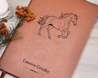 May include: A brown leather journal with a line drawing of a horse running. The journal is personalized with the name "Lauren Crosby".