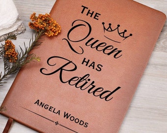 Può includere: Un diario in pelle marrone con il testo "The Queen Has Retired" e una grafica a corona. Il nome "Angela Woods" è inciso sotto il testo.