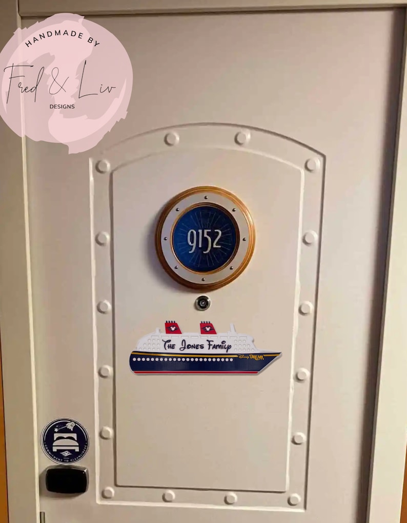 Puede incluir: Puerta blanca con una placa con el n&uacute;mero de habitaci&oacute;n en forma de ojo de buey que dice "9152". Debajo, un letrero con forma de crucero con el texto "The Jones Family" y "Disney Dream". Una pegatina con un icono de cama est&aacute; en la esquina inferior izquierda.