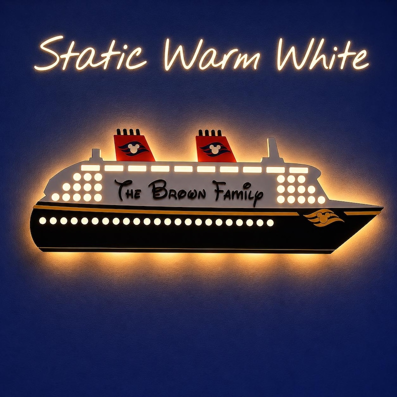 Puede incluir: Una l&aacute;mpara de pared con forma de crucero en negro, blanco y dorado, con el texto "The Brown Family". El barco tiene dos chimeneas rojas con siluetas de Mickey Mouse. Las palabras "Static Warm White" est&aacute;n encima del barco.