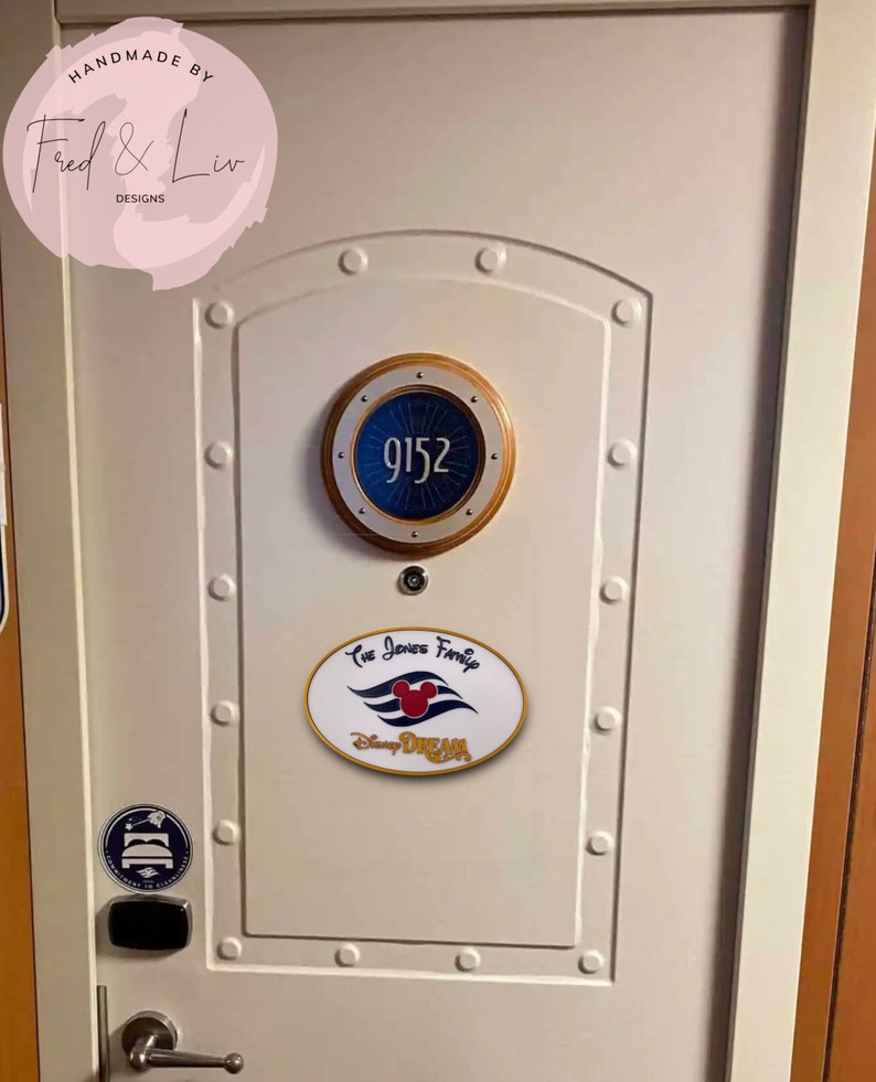 K&ouml;nnte beinhalten: Eine wei&szlig;e T&uuml;r mit einem runden Schild in Gold und Blau mit der Nummer 9152 darauf. Unter dem Schild befindet sich ein wei&szlig;es Oval mit dem Text "The Jones Family" und einem Mickey-Maus-Kopf mit den Worten "Disney Dream" darunter.