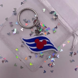 Könnte beinhalten: Ein weißer, blauer und roter Disney Cruise Line Schlüsselanhänger mit einem Mickey Mouse Kopf in der Mitte. Der Schlüsselanhänger ist an einem silbernen Schlüsselring befestigt.