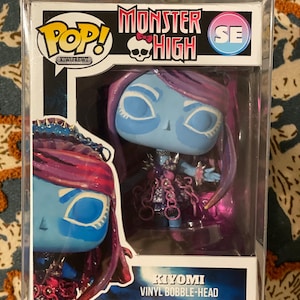 Puede incluir: Figura de vinilo Kiyomi de la serie Monster High, presentada en una caja de plástico transparente. La figura tiene piel azul, pelo morado y viste un atuendo detallado. La caja presenta los logotipos de Pop! y Monster High.