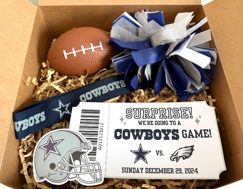 K&ouml;nnte beinhalten: Eine Geschenkbox gef&uuml;llt mit Artikeln zum Thema Dallas Cowboys, darunter ein Football, ein Pompon, ein Lanyard, ein Helm-Aufkleber und ein Ticketstub mit der Aufschrift "&Uuml;berraschung! Wir gehen zu einem Cowboys-Spiel!"  VS.  Sonntag, 29. Dezember 2024.