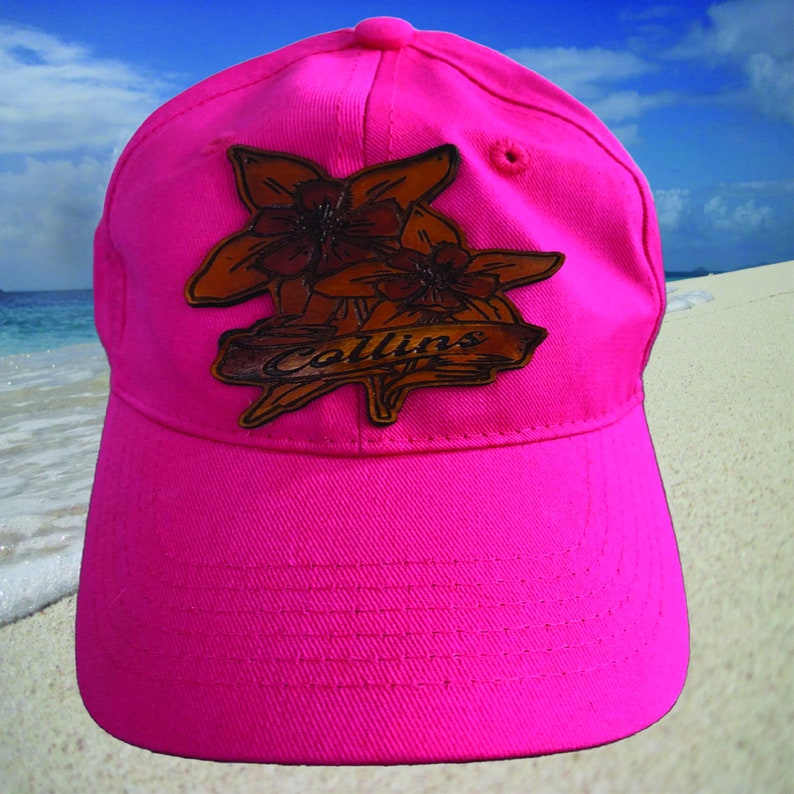 May include: A pink baseball cap with a brown leather patch featuring a floral design and the name "Collins".