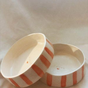 May include: A set of three ceramic mugs with a speckled, matte finish. The mugs are in shades of cream, light gray, and dark gray. Each mug has a simple, minimalist design, perfect for coffee or tea.