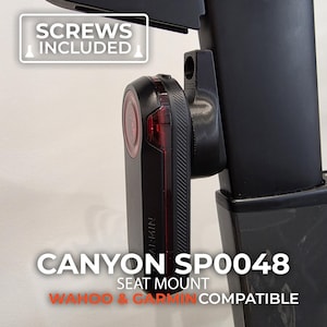May include: Black Canyon SP0048 seat mount for Wahoo & Garmin devices. The mount includes screws and is designed to attach to a bicycle seat post. The device has a red light and the word "Garmin" is visible.