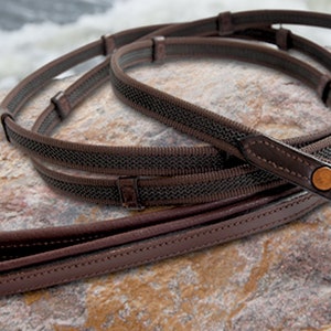 May include: A brown leather dog leash with a black and brown braided strap and a gold metal clip.