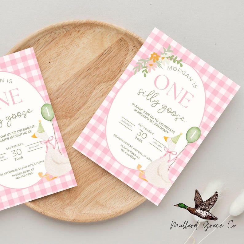 May include: Two pink gingham birthday invitations with the text "ONE silly goose" and "Morgan's 1st Birthday". Each invitation features a watercolor illustration of a goose holding a balloon and wearing a party hat. The invitations are on a wooden tray.