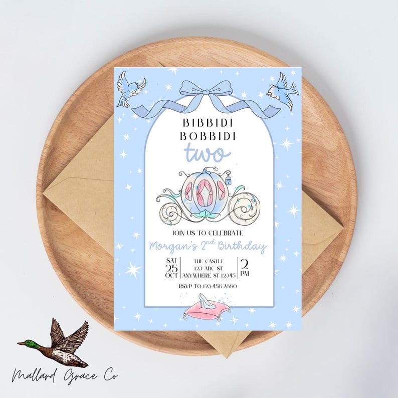 May include: A light blue birthday invitation with the text "Bibbidi Bobbidi Two" and a drawing of a carriage. The invitation is for Morgan's 2nd birthday, with the date, time, and location details. The invitation is on a wooden tray with an envelope.