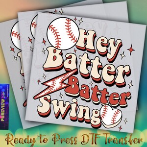 May include: A stack of three gray square DTF transfer sheets with a baseball theme. The design features a baseball, lightning bolt, and the words "Hey Batter Batter Swing" in red and cream colors. Small star shapes are scattered around the text.