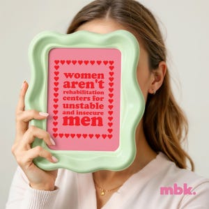 May include: A light green frame with a pink background and the text "women aren't rehabilitation centers for unstable and insecure men" in red letters surrounded by red hearts.