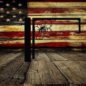 May include: Black metal wall hook with a flower design. The hook is mounted against a weathered wood background with an American flag design.