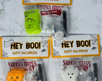 Könnte beinhalten: Halloween-Geschenktüten mit dem Text "HEY BOO! HAPPY HALLOWEEN!". Jede Tüte enthält eine Marshmallow-Figur, Swiss Miss-Kakao-Mix, Schokostreusel und einen Hershey's Kiss. Die Figuren sind Frankenstein, ein Kürbis und ein Geist.