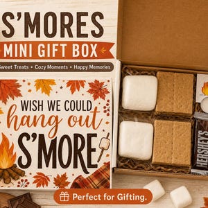May include: A S'mores mini gift box featuring a cardboard lid with autumn leaves, a campfire illustration, and the text "WISH WE COULD hang out S'MORE". The open box contains graham crackers, white marshmallows, a Hershey's bar, and a tea light.