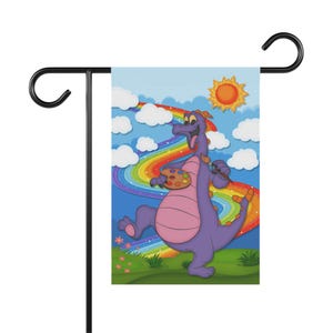 May include: A purple dragon with a paintbrush and a paint palette stands in front of a rainbow with a bright yellow sun in the background. The dragon is smiling and has a happy expression. The background is a blue sky with white clouds.