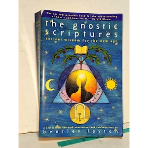 以下が含まれることがあります： ベントレー・レイトン著『The Gnostic Scriptures』のペーパーバック。青い表紙には、円の中の人のシルエット、木、三日月、太陽、鍵のあるアーチのイラストが中央に描かれており、ギリシャ語のテキストも含まれています。
