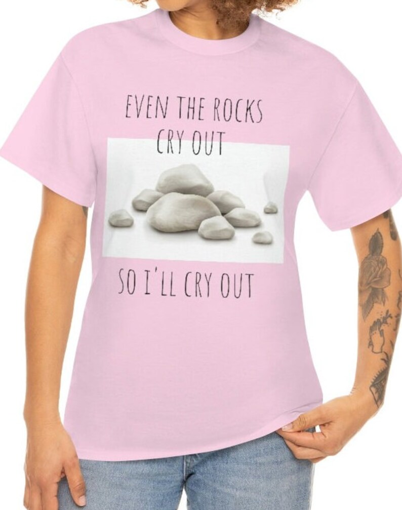 Peut inclure: T-shirt rose avec un graphique blanc de rochers et le texte "Even the rocks cry out so I'll cry out".