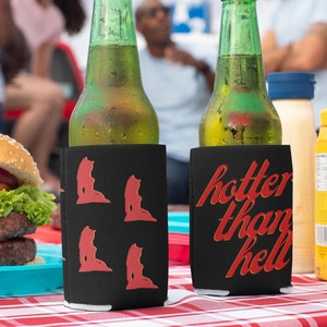 Può includere: Due bottiglie di vetro verde con guaine isolanti nere. Una guaina ha una grafica rossa di un'aragosta e l'altra ha il testo "hotter than hell" in rosso.