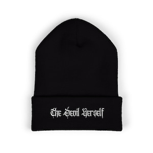 Puede incluir: Gorro negro con la frase "The Devil Herself" en blanco y fuente gótica. El gorro es de estilo ajustado, perfecto para el frío. El texto está centrado en el borde doblado.
