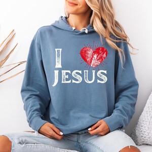 May include: A blue hooded sweatshirt with the words "I love Jesus" in white with a red heart graphic.