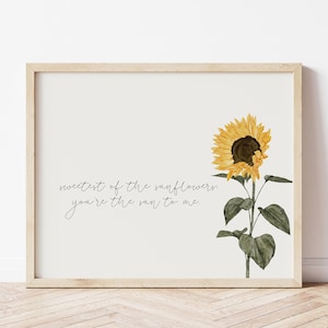 Może przedstawiać: Wydruk w ramie z akwarelową ilustracją słonecznika i tekstem "Sweetest of the sunflowers, you're the sun to me".