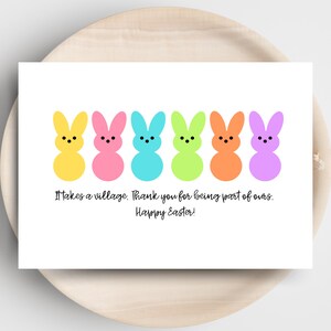 May include: A white card with six colorful bunny shapes in yellow, pink, blue, green, orange, and purple. The card has the text "It takes a village. Thank you for being part of ours. Happy Easter!" on it.