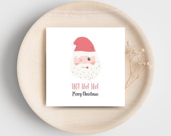 Peut inclure: Carte de Noël carrée avec un dessin de Père Noël qui cligne de l'œil et tire la langue. Le texte "HO! HO! HO!" et "Merry Christmas" est en rouge et noir sur fond blanc.
