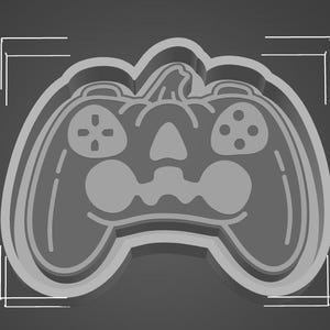 Op de afbeelding: Een grijze 3D-geprinte pompoen in de vorm van een videogamecontroller. De pompoen heeft een gesneden gezicht met twee ogen, een neus en een mond.
