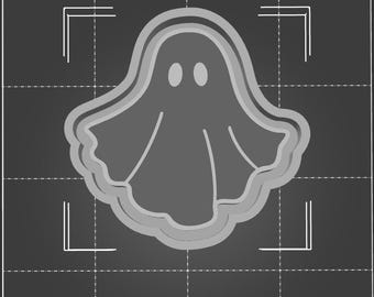 May include: A gray ghost cookie cutter with a rounded shape and two small circles for eyes. The cutter is on a black and white grid background.