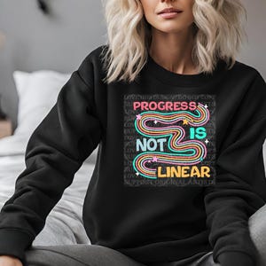 May include: Black sweatshirt with a colorful graphic design that says "Progress is not linear".