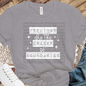 Può includere: Maglietta grigia con il testo "Feelings are the eraser of boundaries" stampato sul davanti. Il testo è circondato da un motivo ripetuto di "Love this design? Do not copy. Support original artists."