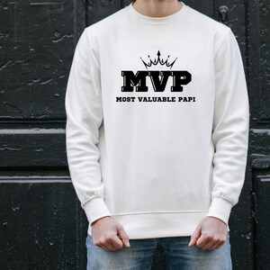 May include: White sweatshirt with black text that reads "MVP Most Valuable Papi" and a crown graphic above the text.
