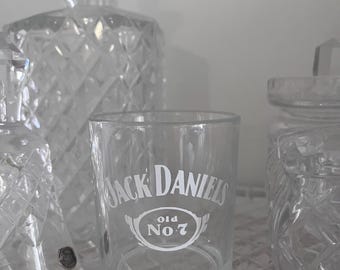 May include: A clear glass shot glass with the words "Jack Daniel's Old No. 7" printed on the side.