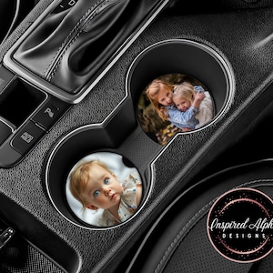May include: Two car coasters with personalized photos. The first coaster features a photo of two young girls smiling. The second coaster features a photo of a young child with brown hair and blue eyes. The coasters are round and have a white background.