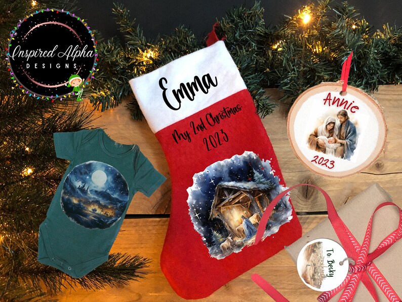 May include: A set of personalized Christmas gifts featuring a red stocking with a nativity scene, a green baby onesie with a moonlit scene, a round wooden ornament with a nativity scene and the name "Annie", and a round tag with the text "To Becky".
