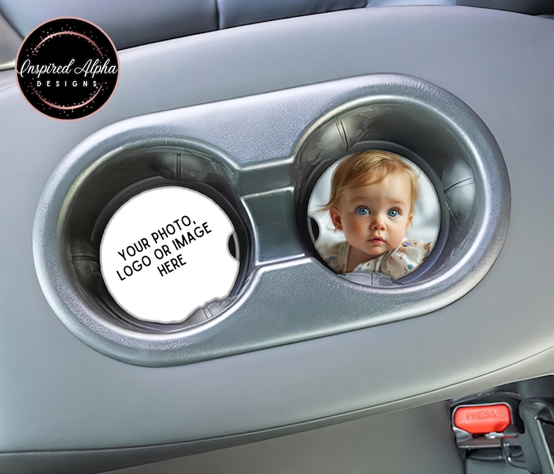 May include: Two gray car cup holders with a white round coaster in each. The coaster on the left says "YOUR PHOTO, LOGO OR IMAGE HERE". The coaster on the right has a photo of a baby girl with blonde hair and blue eyes.