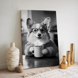 May include: Black and white photo of a corgi wearing glasses and a sweater, holding a cup of coffee. The corgi is sitting at a table with a steaming cup of coffee.