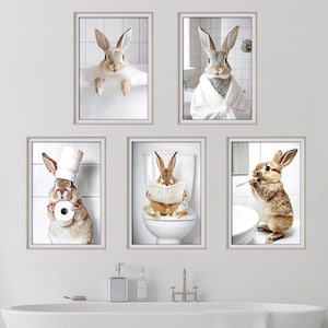 Peut inclure: Cinq impressions encadrées représentant des lapins dans des scènes de salle de bain. Un lapin est dans une baignoire, un autre en peignoir, un troisième portant un chapeau de chef, un quatrième sur des toilettes lisant et le dernier se brossant les dents.