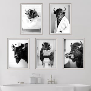 Op de afbeelding: Een set van zes zwart-wit ingelijste prints met een bizon in verschillende badkamersituaties. De bizon is te zien terwijl hij een bad neemt, een krant leest, zijn tanden poetst en een badjas draagt.