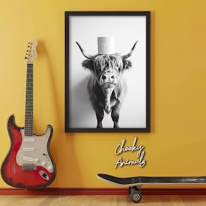 May include: Black and white photograph of a Highland cow wearing a toilet paper roll as a hat. The image is framed and has the text "Cheeky Animals" below it.