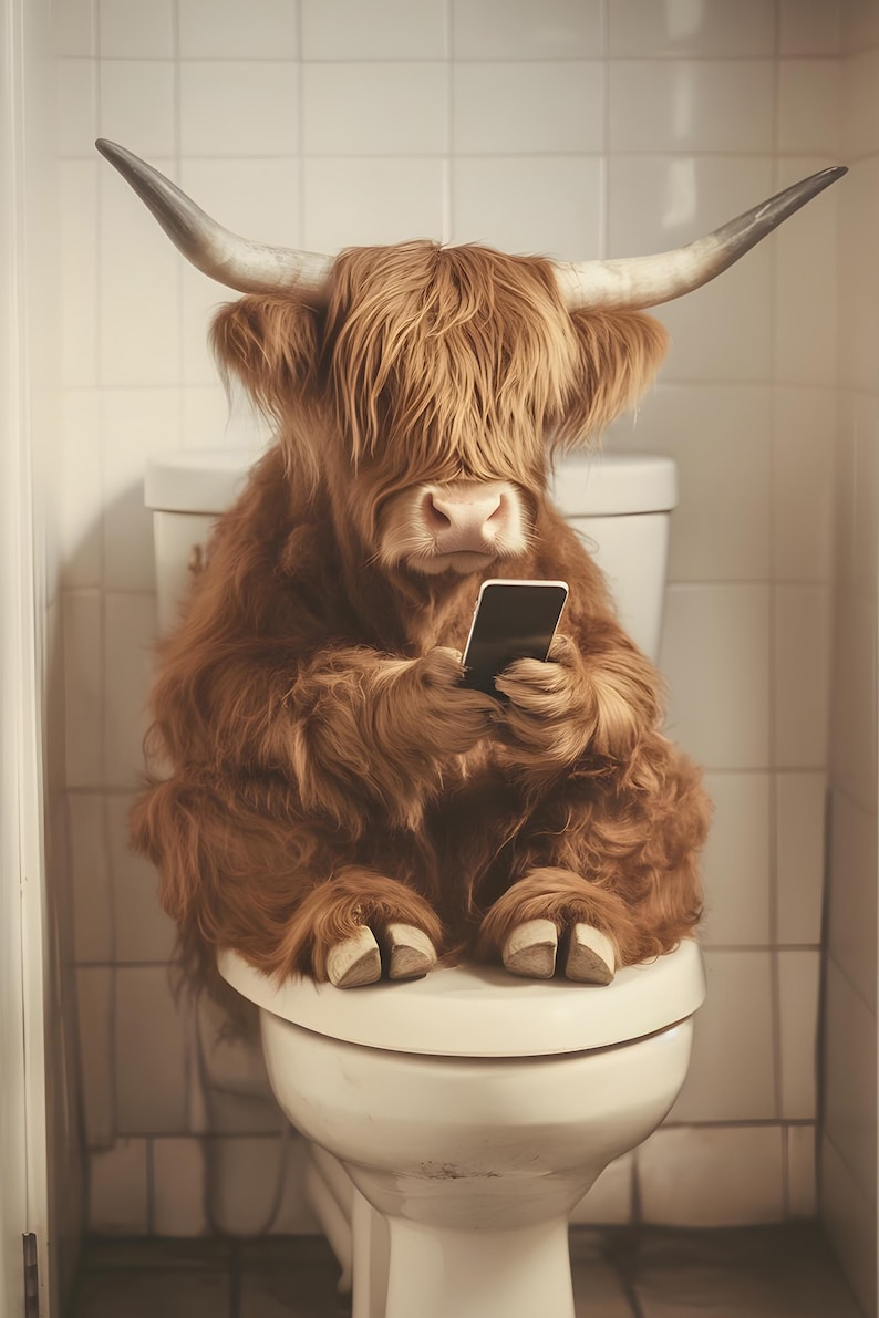 May include: A brown and white Highland cow sits on a white toilet seat, holding a black smartphone in its front paws.