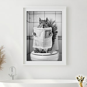 May include: Black and white framed print featuring a squirrel sitting on a toilet, reading a newspaper. The image is a humorous depiction of a squirrel in a bathroom setting, with a white frame and a neutral background.