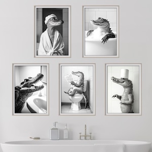 May include: Set of five black and white framed prints featuring a crocodile in various bathroom settings. The crocodile is wearing a bathrobe, taking a bath, reading a book on the toilet, brushing its teeth, and standing in a bathroom.