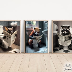 May include: Three framed prints featuring a bat, a red panda, and a raccoon, each sitting on a toilet and reading a newspaper. The prints are set against a white wall.